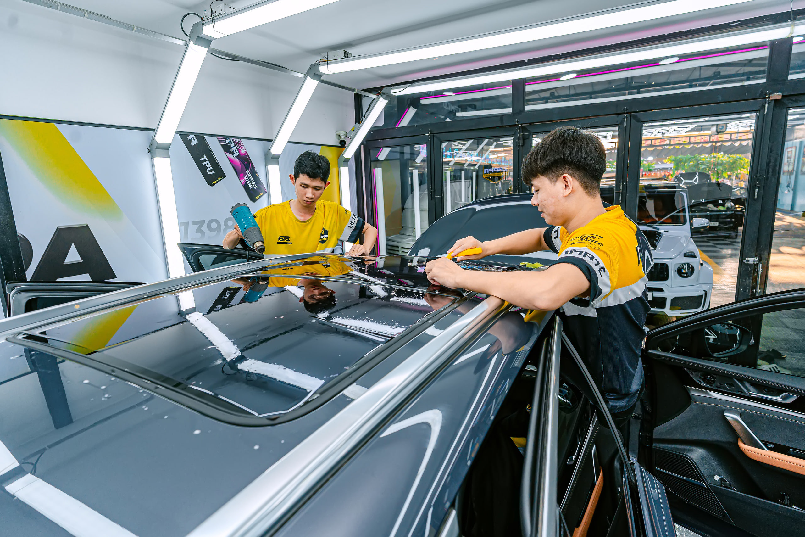Hai kỹ thuật viên dán phim cách nhiệt kính nóc trong phòng kín ở Store Detailing Tân Phú