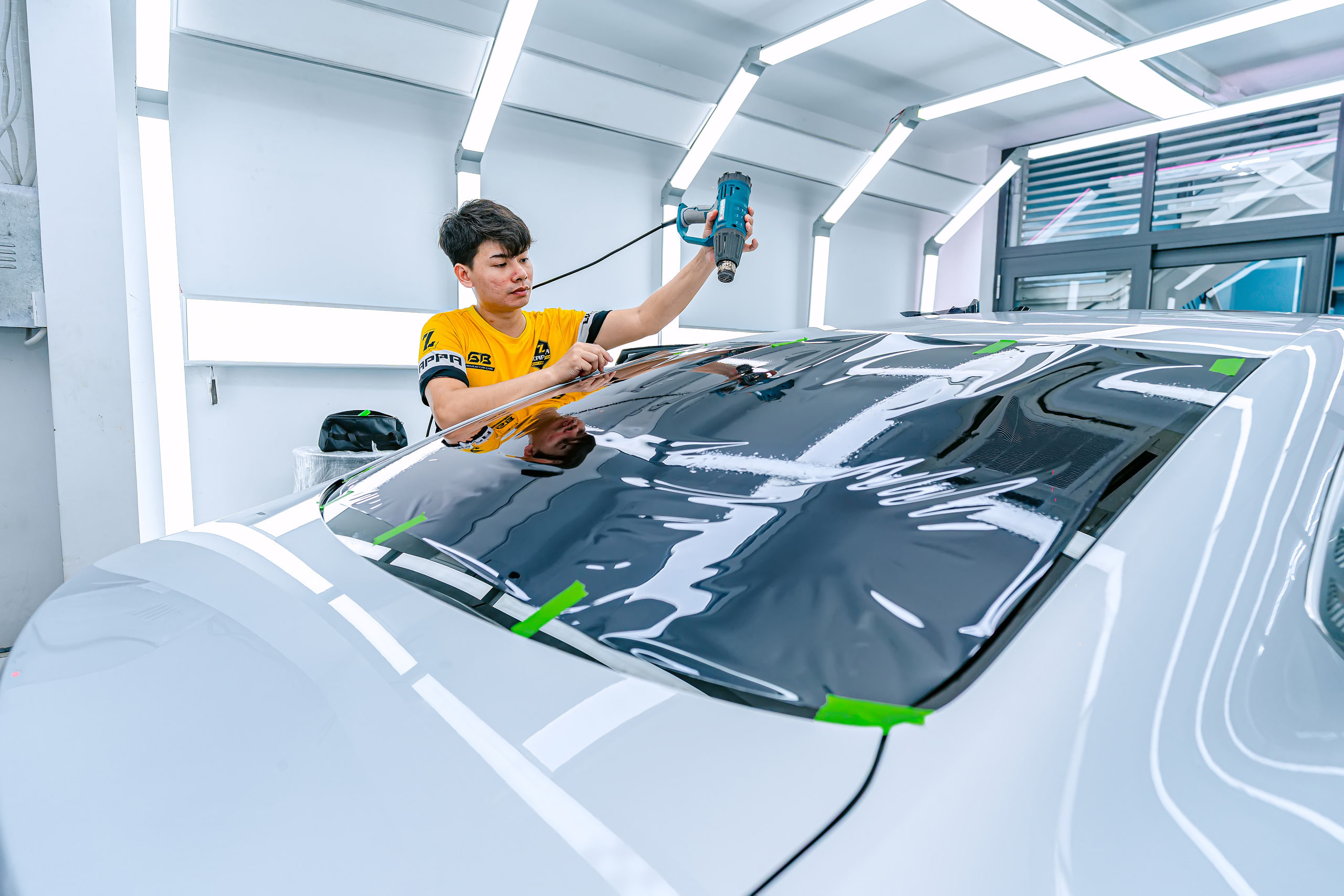 Kỹ thuật viên khò định hình phim cách nhiệt trên kính lưng xe BYD tại Store Detailing Bình Tân