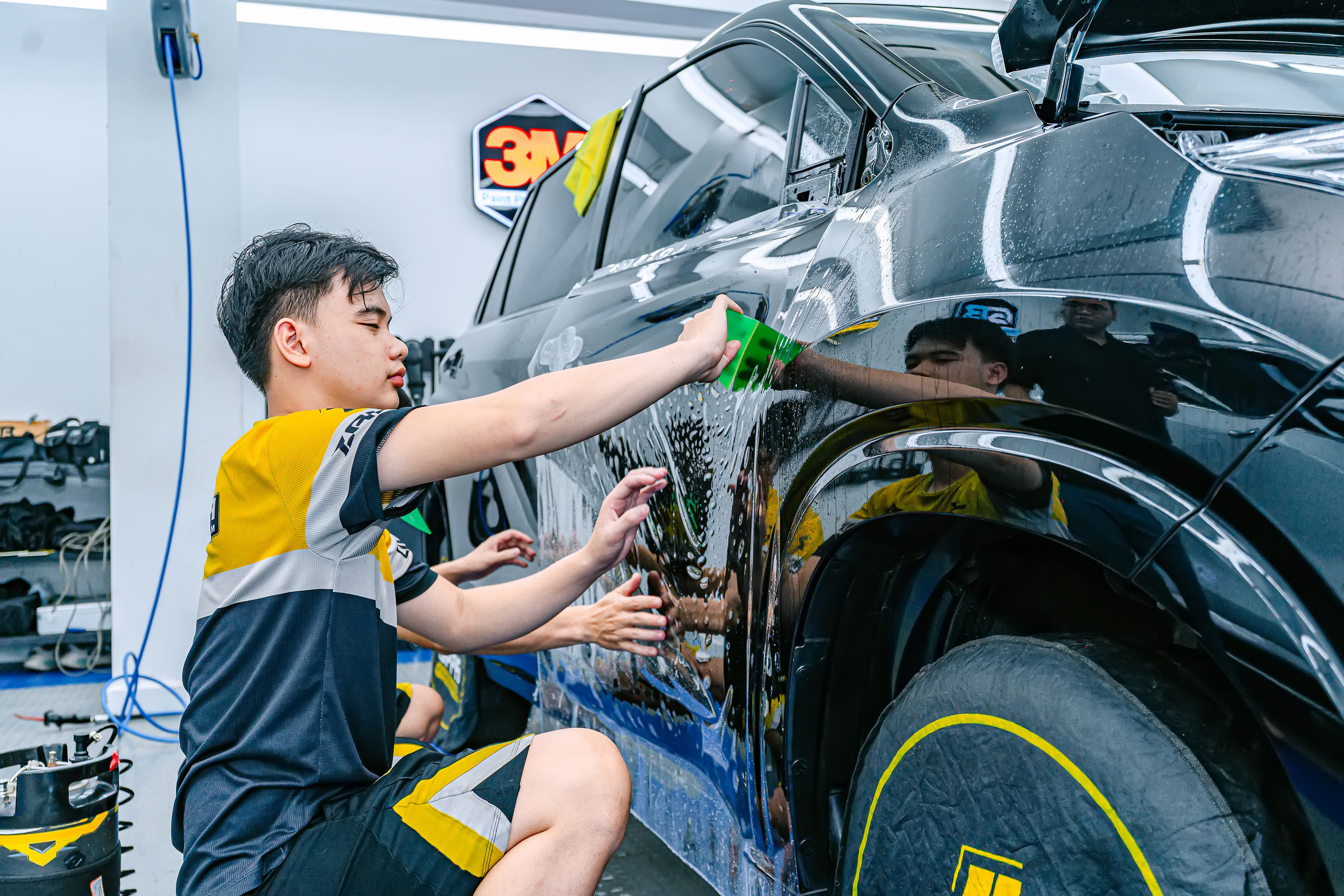 Kỹ thuật viên miết phim PPF hông xe Toyota Innova Cross tại Store Detailing Bình Tân
